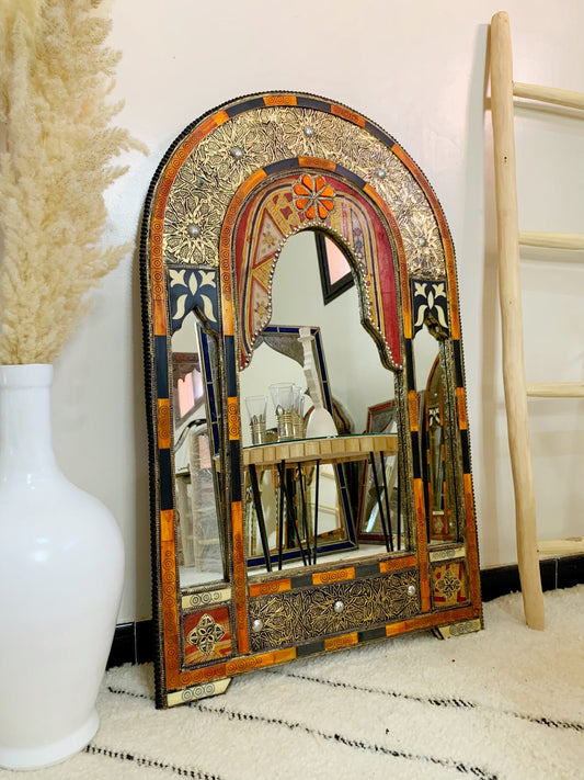 a decorative mirror sitting next to a white vase