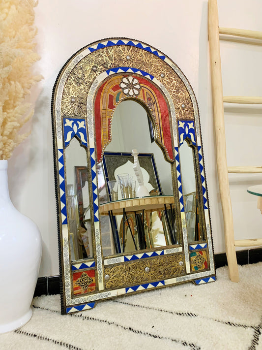 a mirror sitting on top of a floor next to a vase