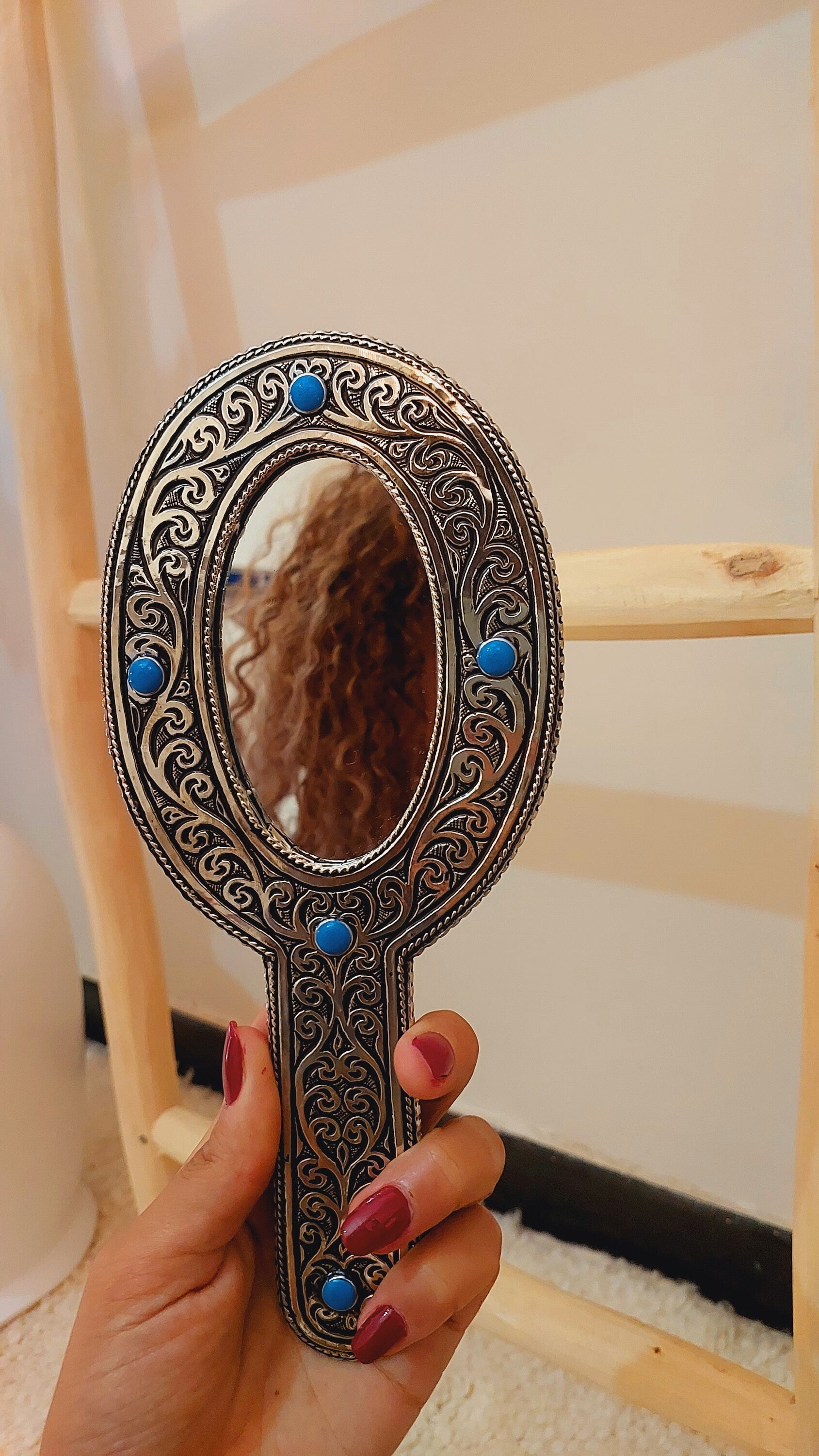 a woman's hand holding a mirror with a reflection of a woman's