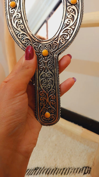 a woman's hand holding a mirror with a design on it