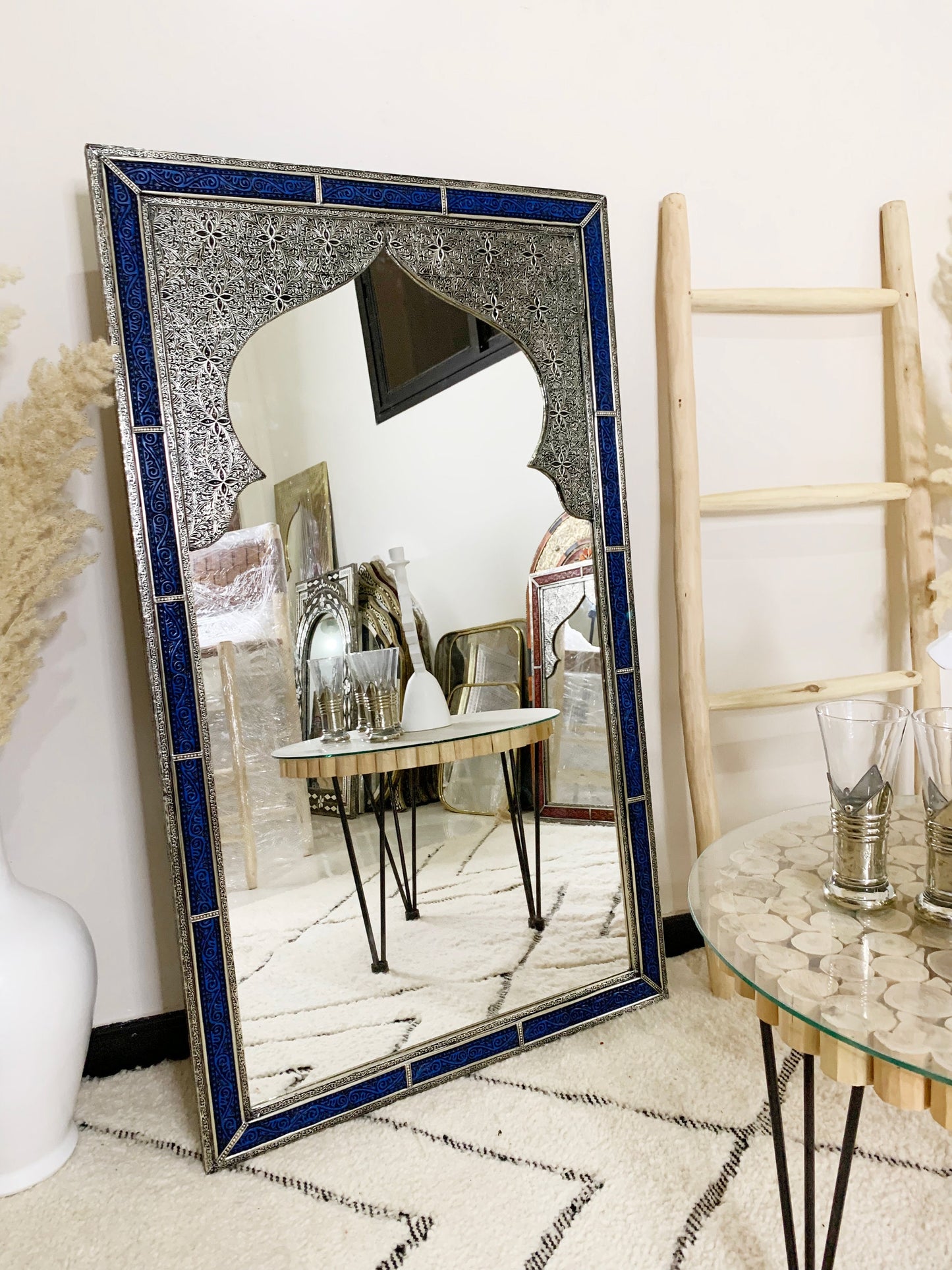 a mirror sitting on top of a table next to a vase