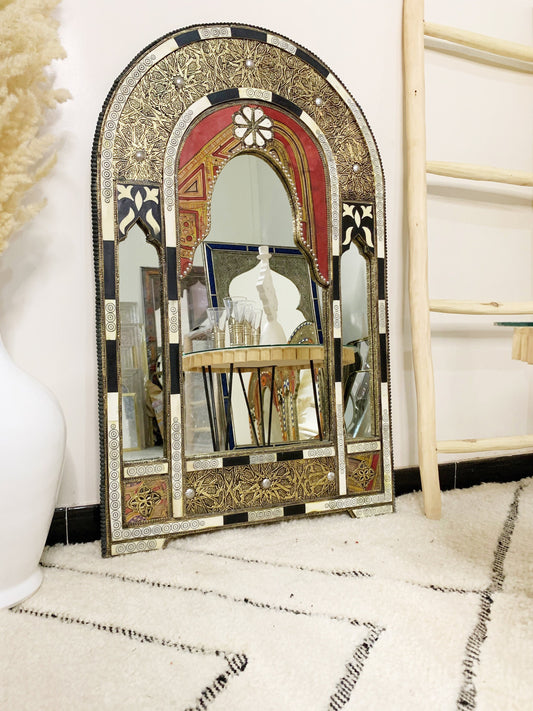 a mirror sitting on top of a rug next to a white vase