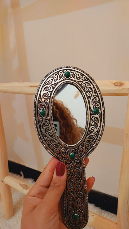 a hand holding a mirror with a woman's reflection in it