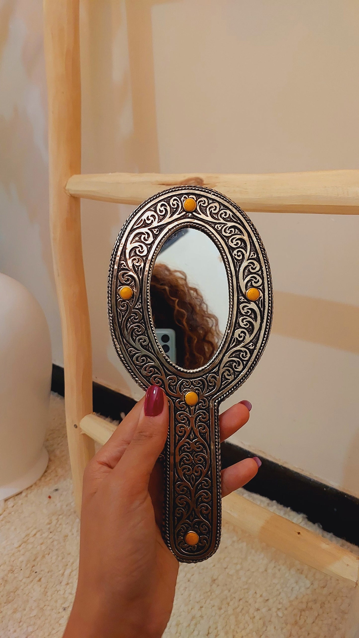 a hand holding a mirror with a reflection of a woman's hair