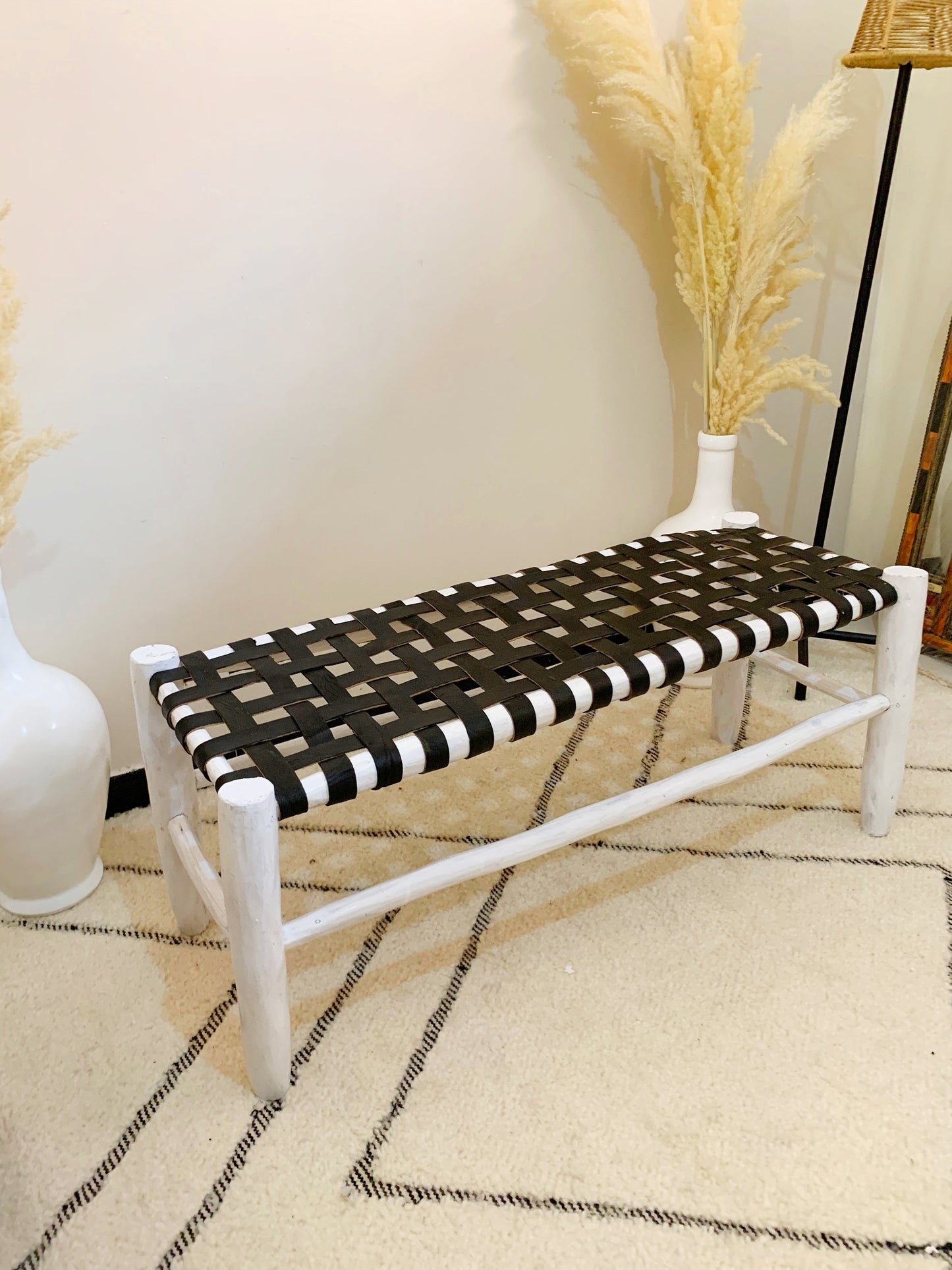 a black and white bench next to a white vase