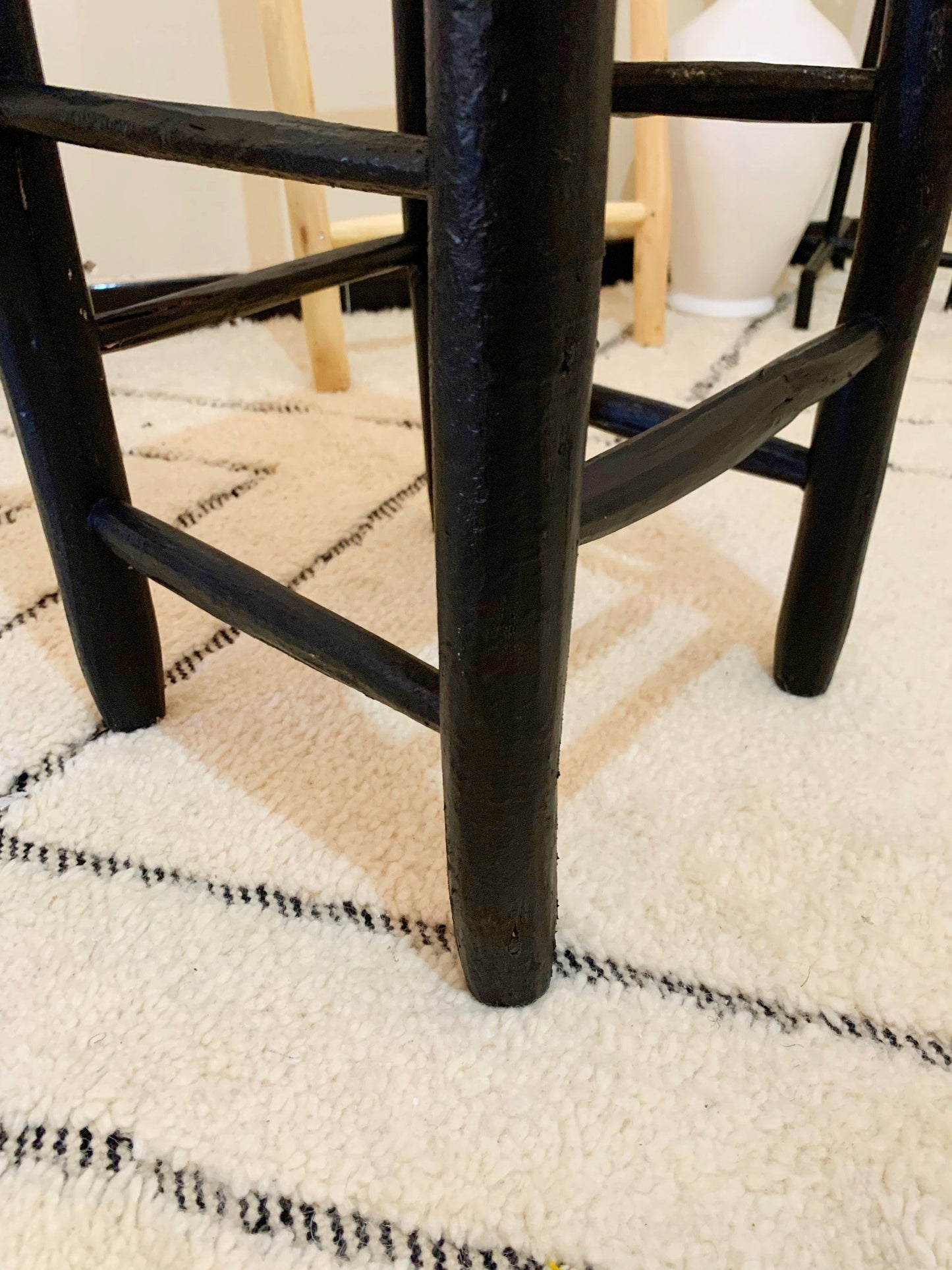 a black stool with a white rug on the floor