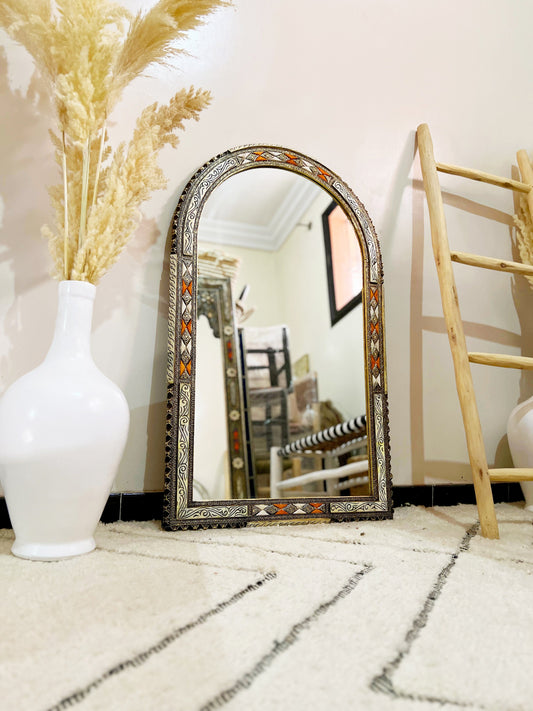 a white vase sitting next to a mirror on a floor