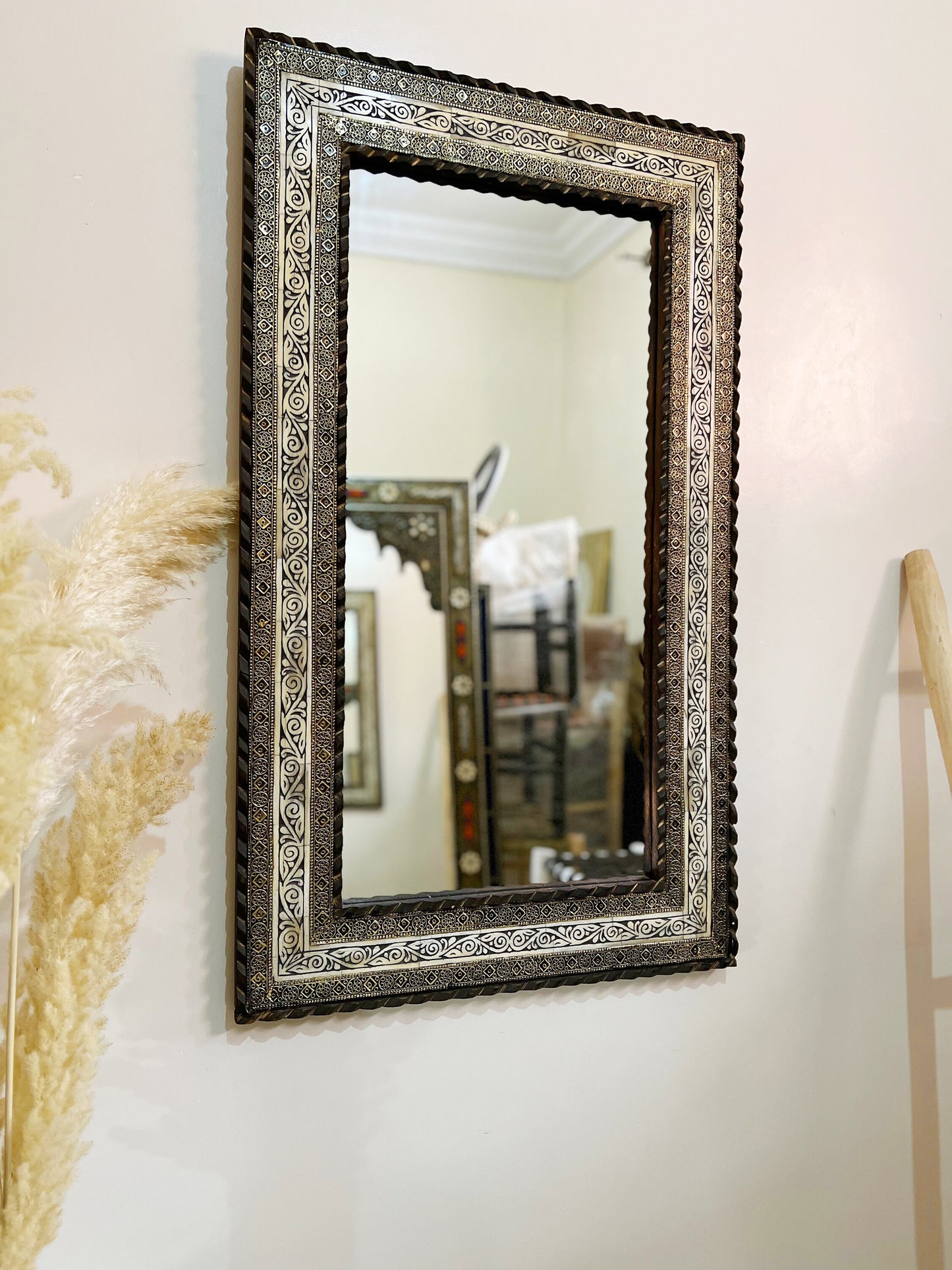 a mirror hanging on a wall next to a plant