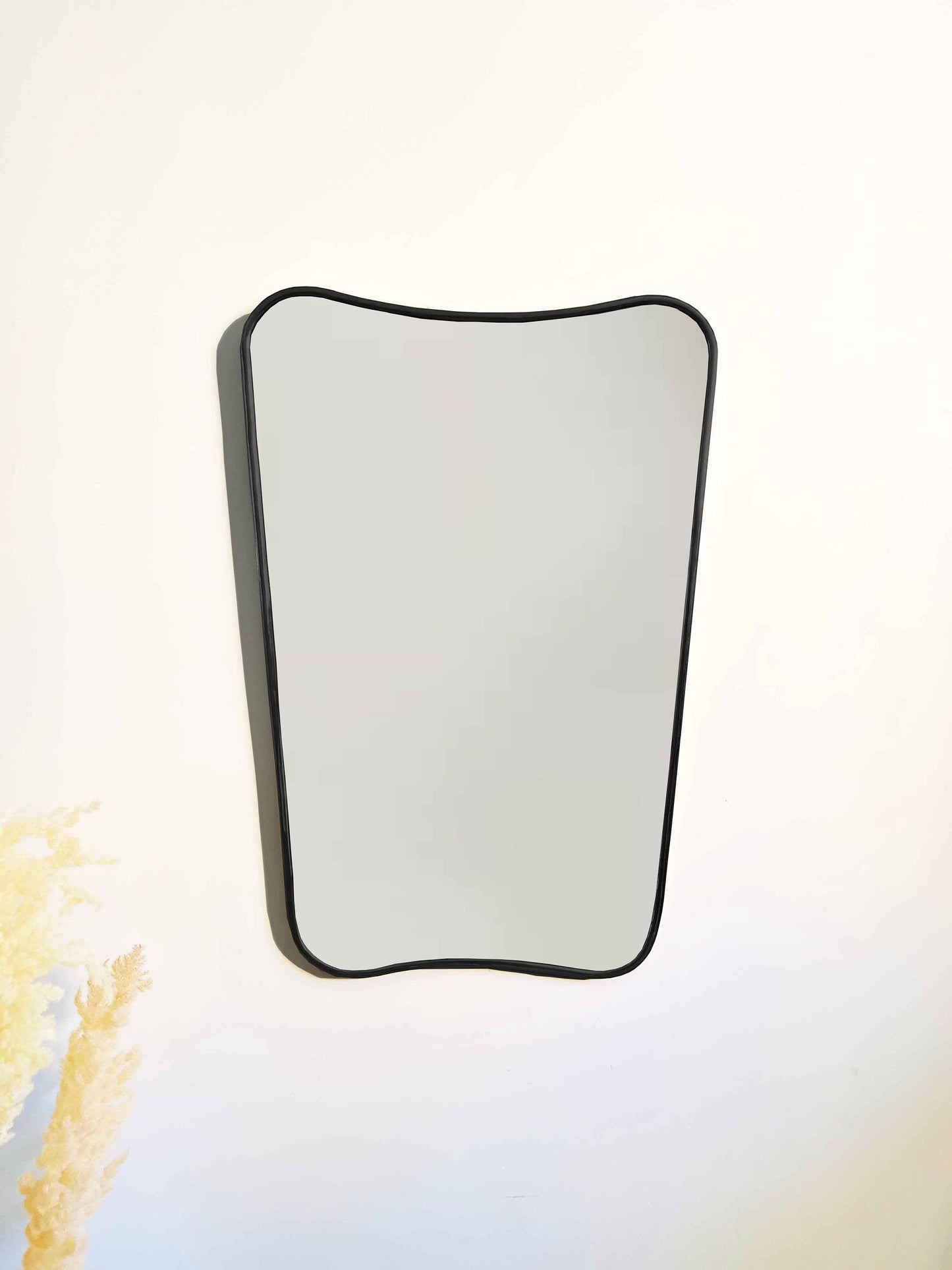 a white wall with a mirror hanging on it