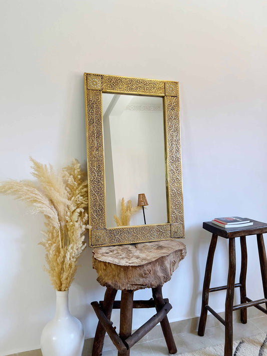 a brass mirror sitting on top of a wooden stool