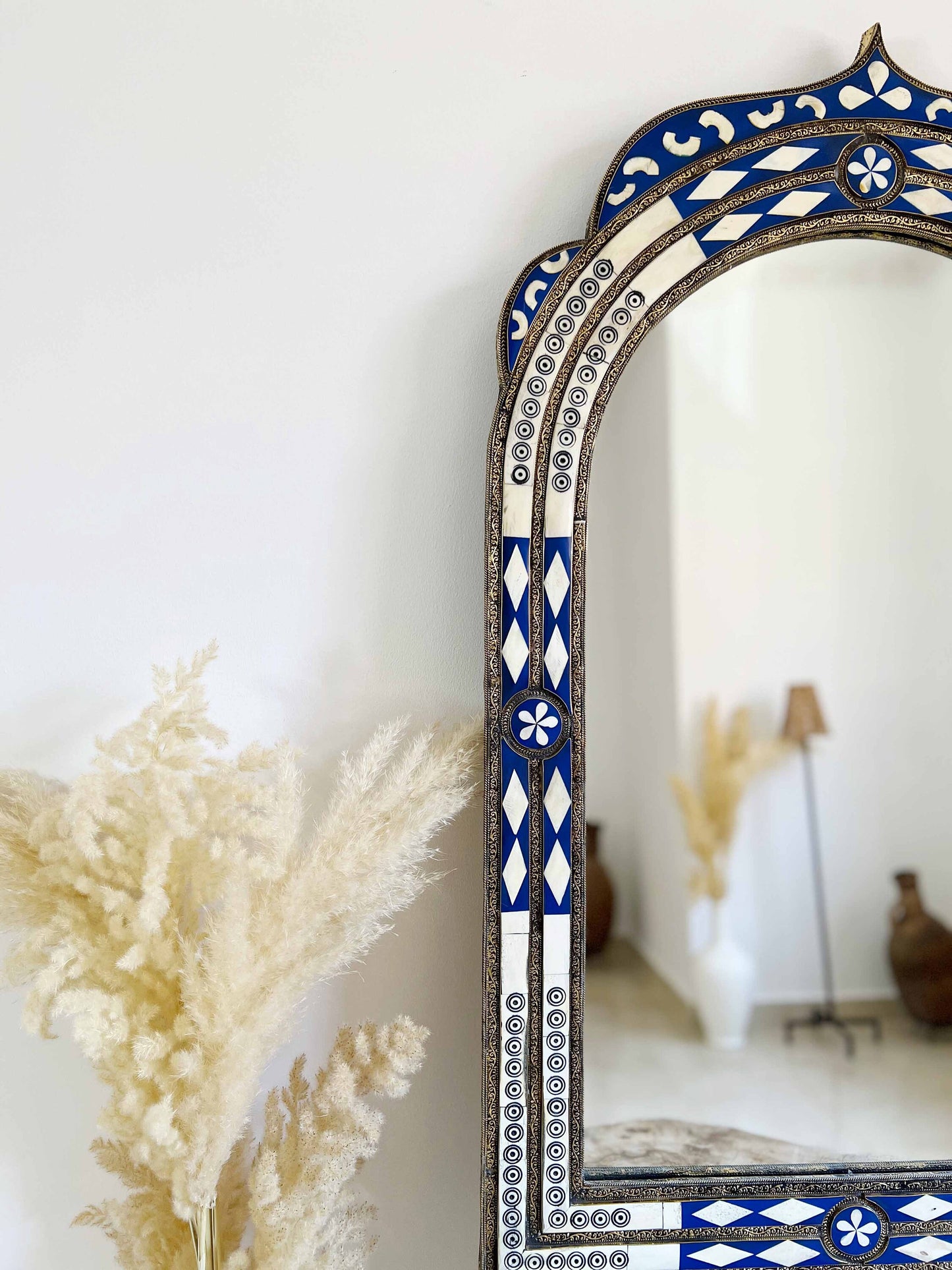 a blue and white mirror sitting next to a plant