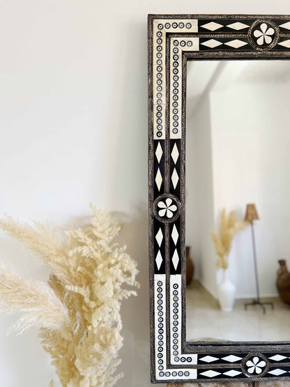 a mirror sitting on top of a table next to a plant