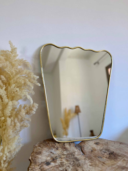 a brass mirror sitting on top of a wooden table