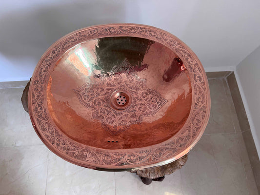 a large copper sink in a bathroom next to a white wall