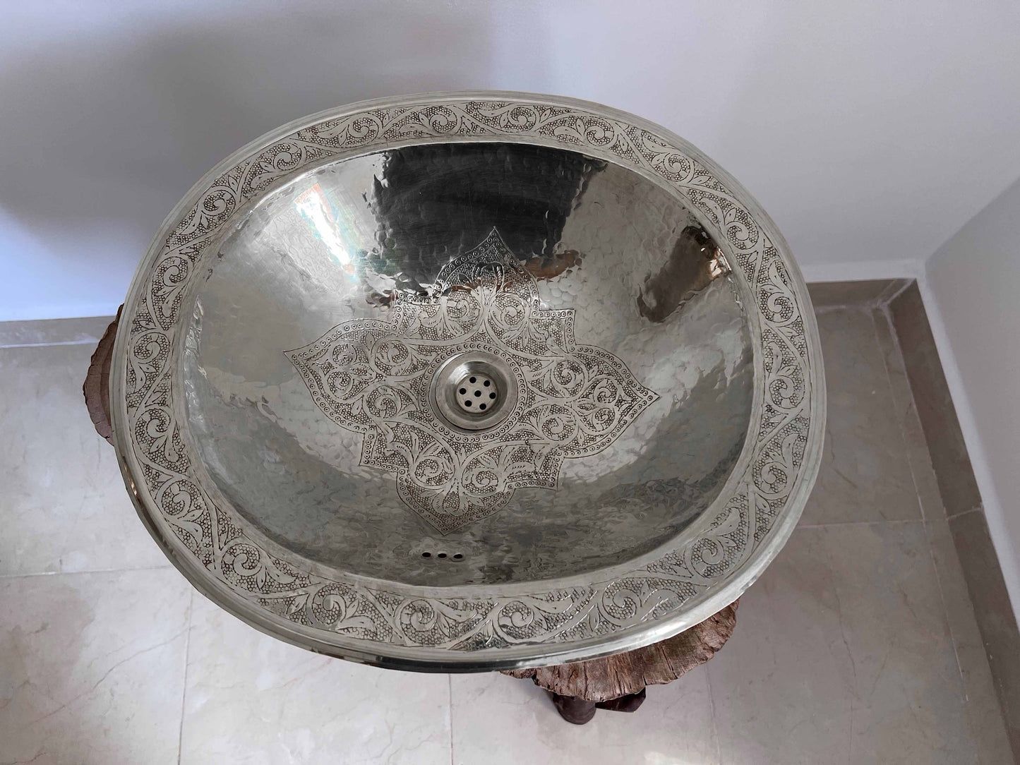 a silver sink sitting on top of a white tiled floor