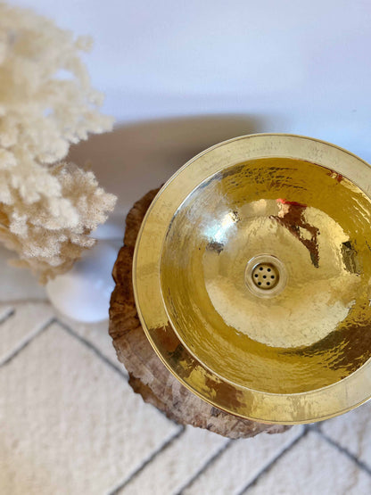 a golden bowl sitting on top of a piece of wood