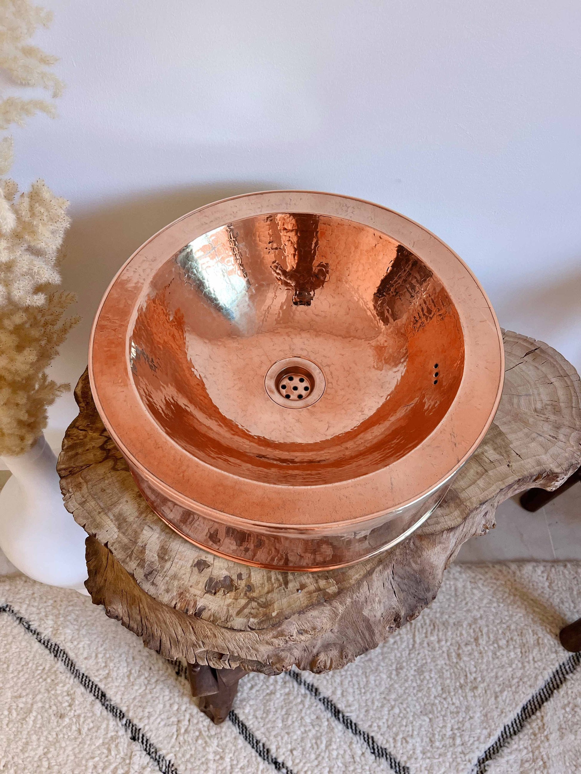 a copper sink sitting on top of a tree stump