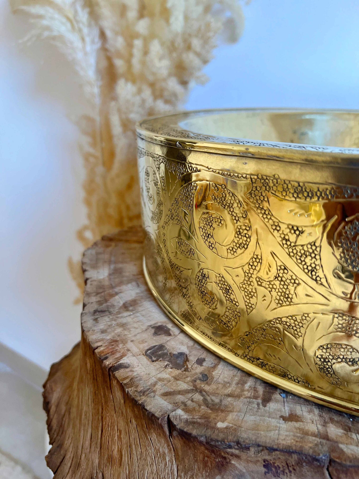 a metal bowl sitting on top of a wooden stump