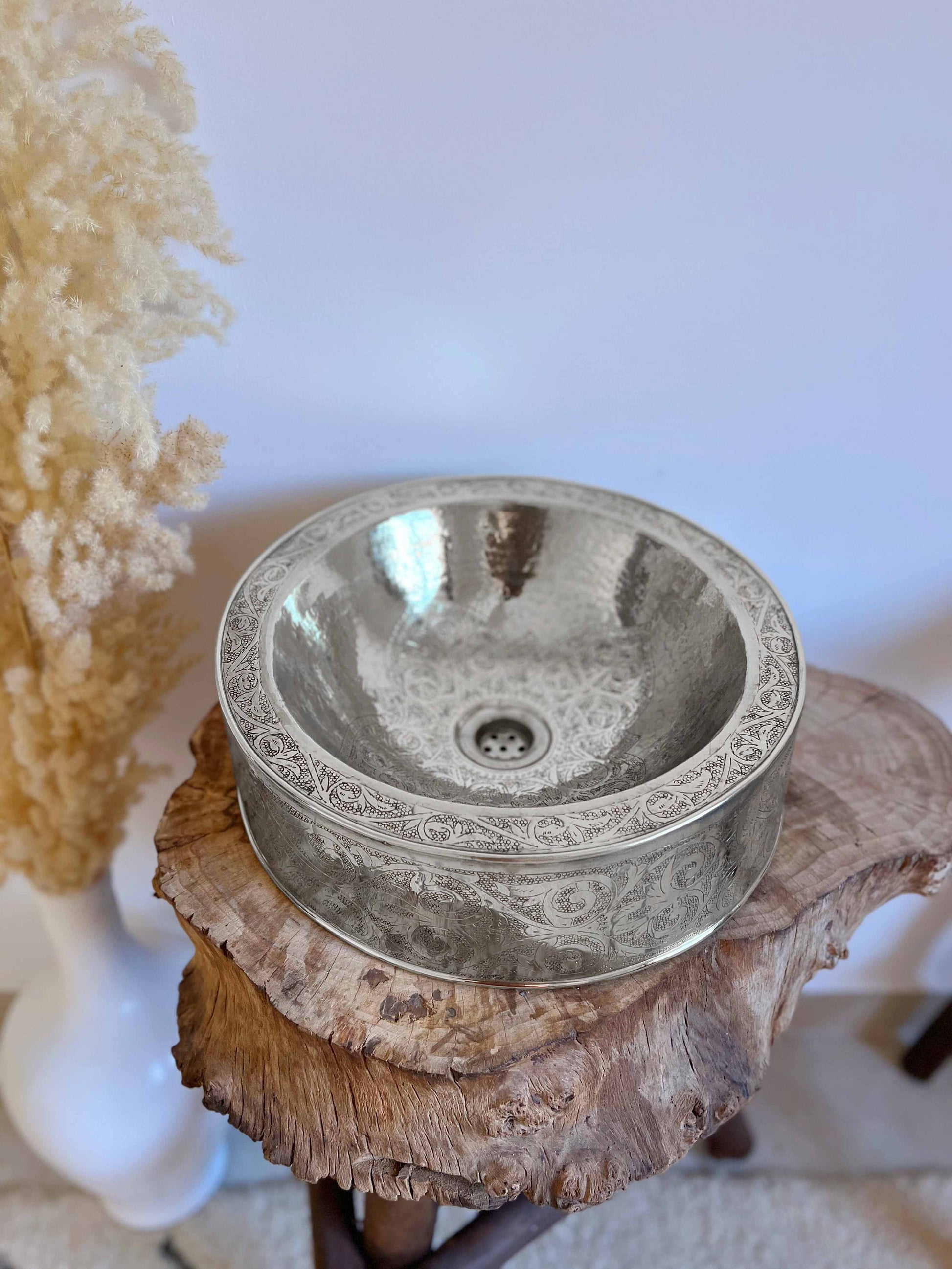 a bowl shaped sink sitting on top of a tree stump