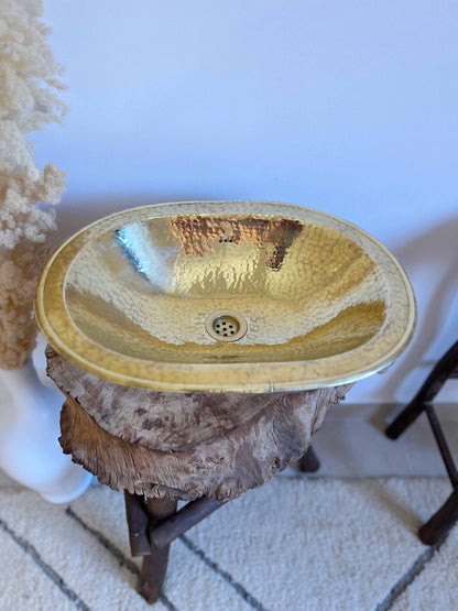 a gold sink sitting on top of a wooden table