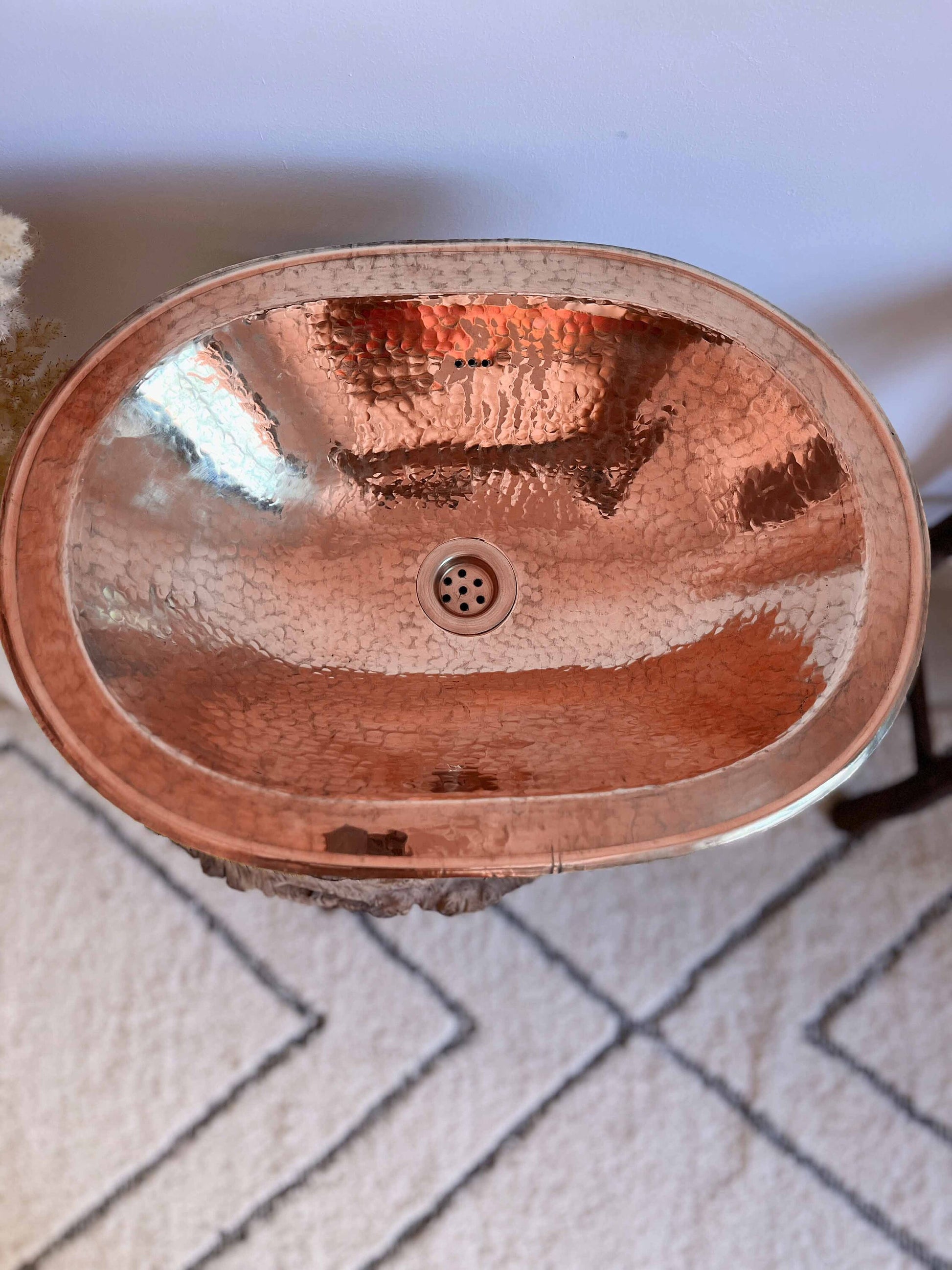 a copper sink sitting on top of a white rug