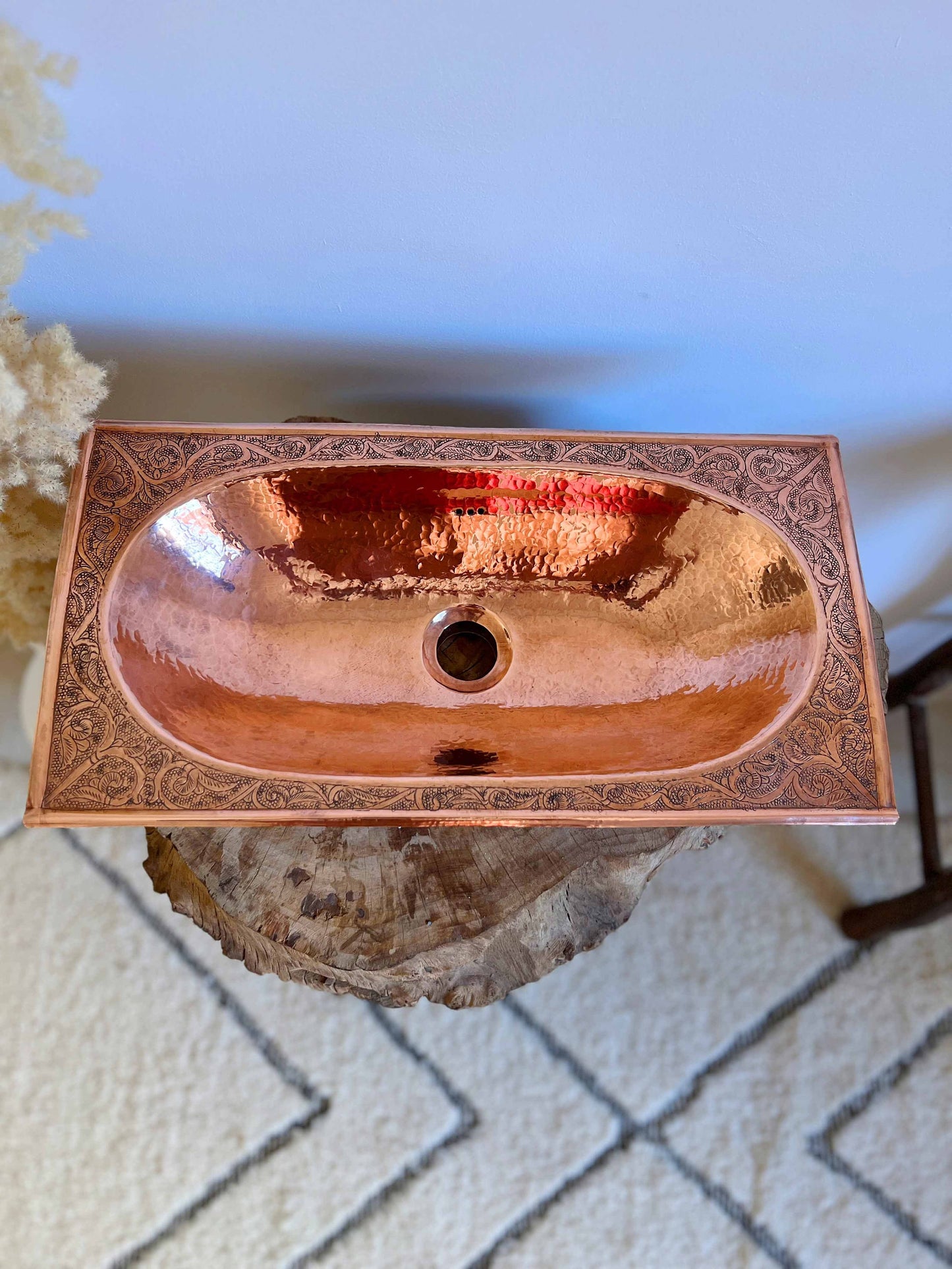 a copper sink sitting on top of a tree stump