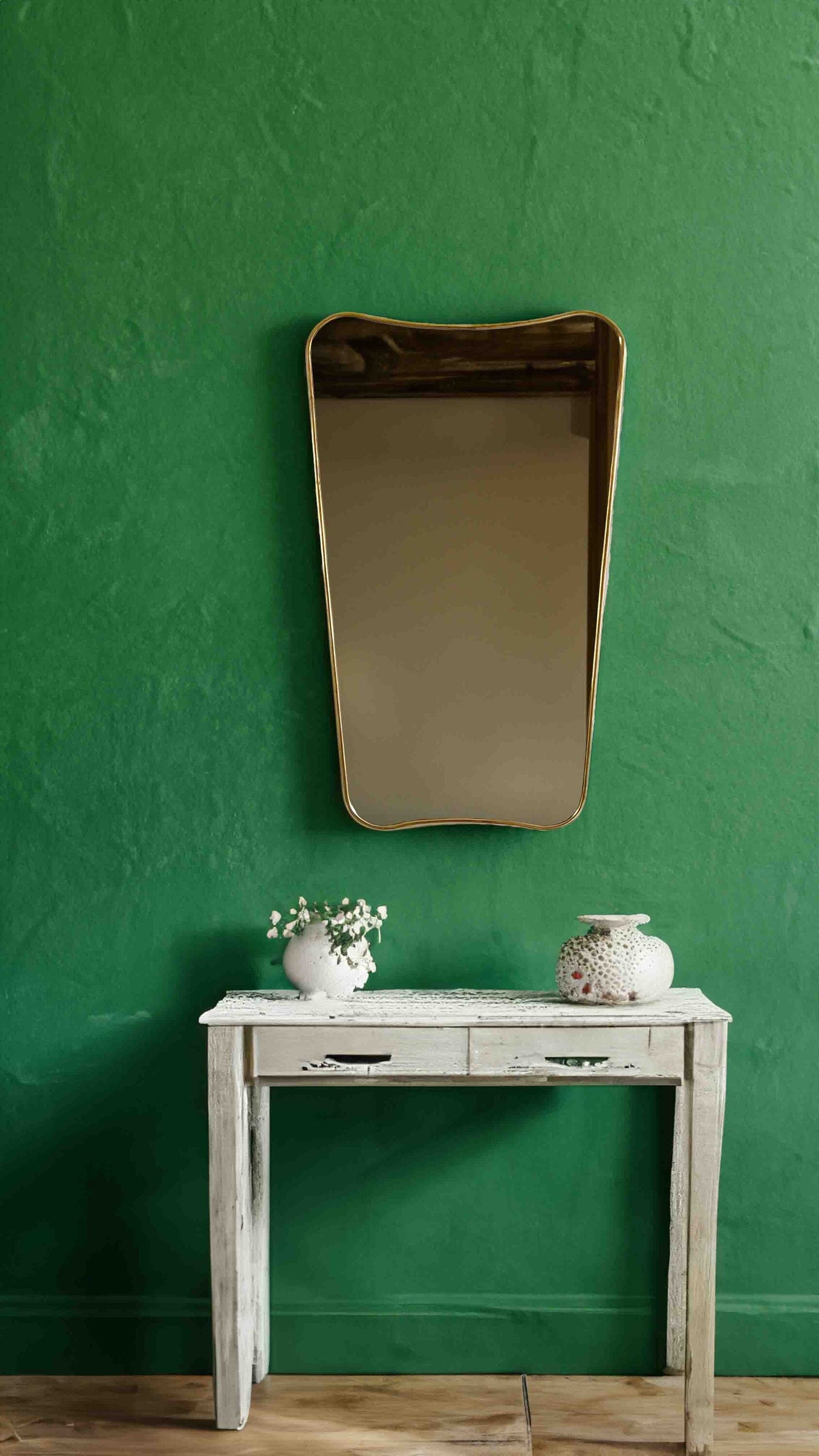 a white table with a mirror and vases on top of it