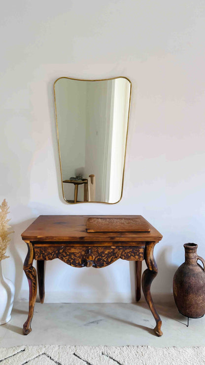 a wooden table with a brass mirror on the wall