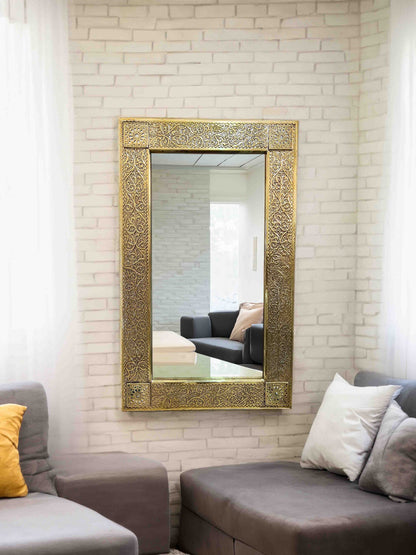 a living room with a couch and a brass mirror