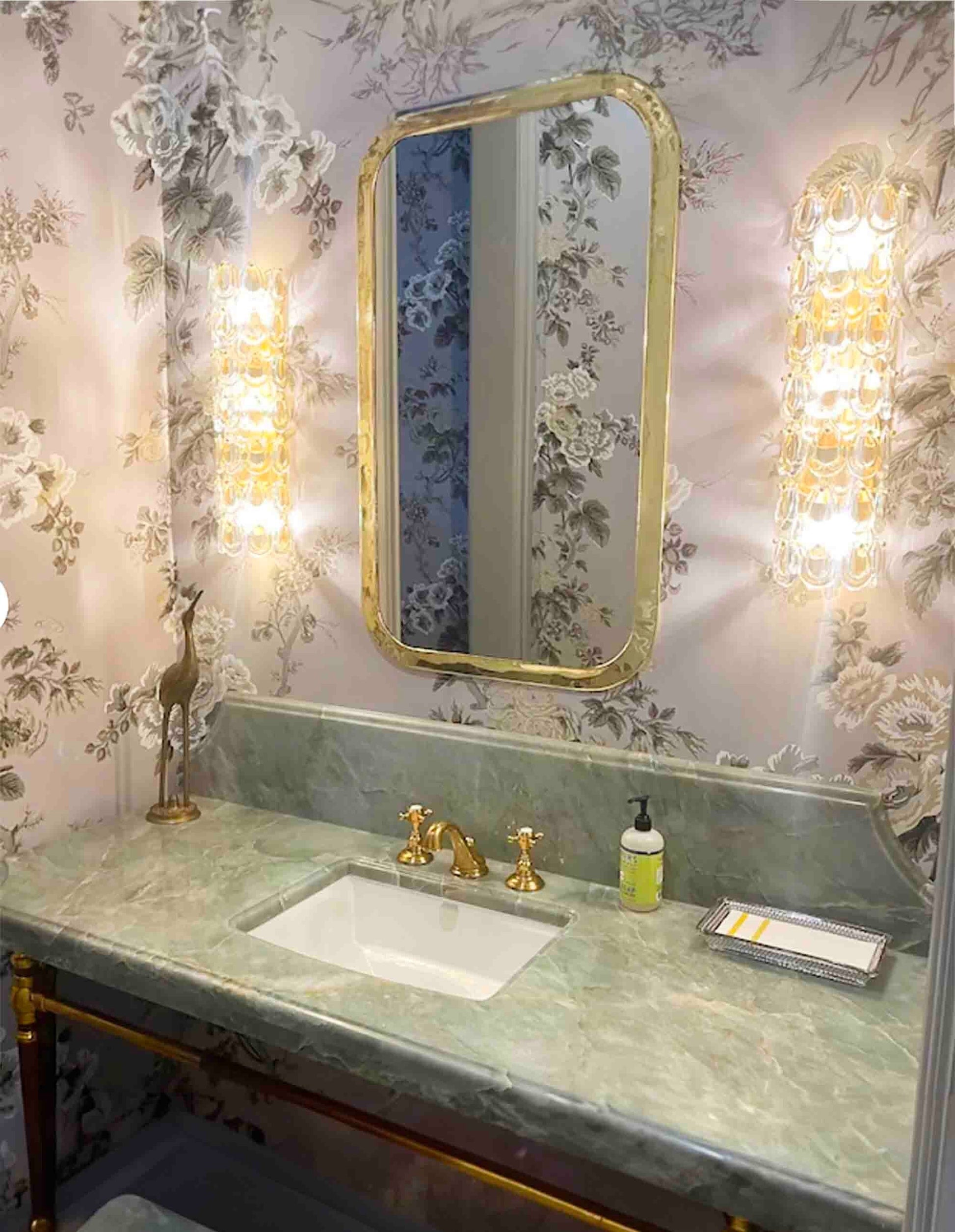 a bathroom with a sink and a brass mirror