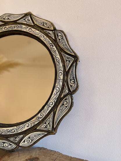 a round mirror sitting on top of a wooden table