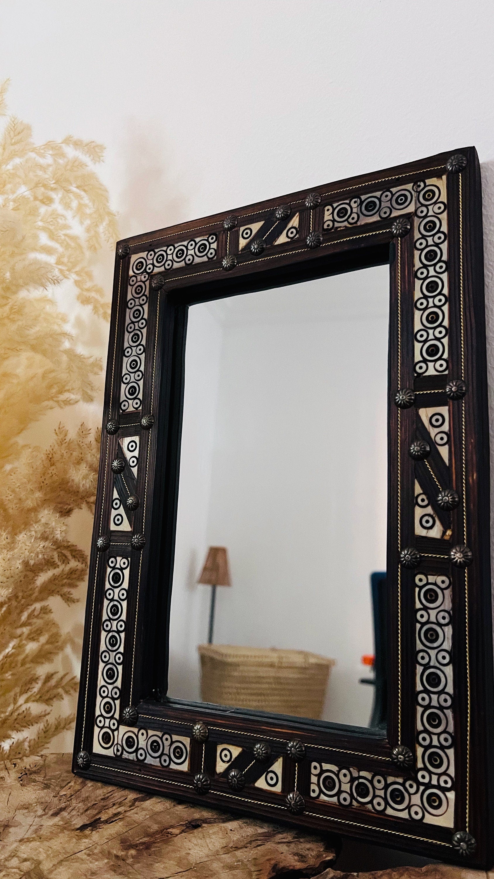 a mirror sitting on top of a table next to a lamp